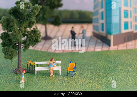 Madre con i bambini nel parco con gli imprenditori in background Foto Stock