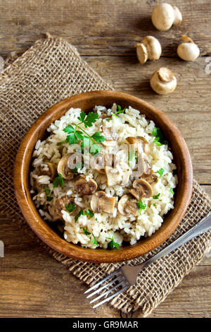 Risotto ai funghi con il prezzemolo nel recipiente di legno vicino fino Foto Stock