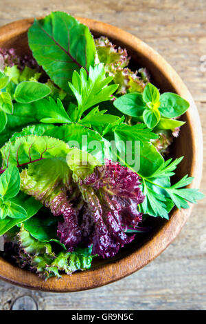 Organico fresco verde insalata mista lascia oltre rustico sfondo di legno Foto Stock