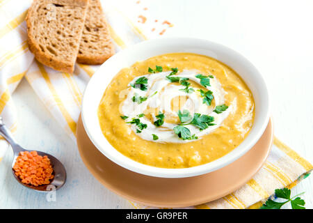 Crema di lenticchie zuppa con crema di formaggio e prezzemolo nel recipiente oltre rustico sfondo di legno Foto Stock