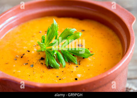 Verdure zuppa di pomodoro e carote in vaso di ceramica oltre rustico sfondo di legno Foto Stock