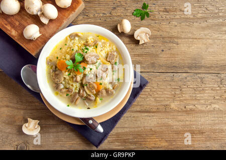 In casa zuppa di funghi con miglio e verdure nella ciotola bianco su sfondo di legno con spazio di copia Foto Stock