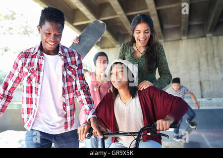 Amici di adolescenti con skateboard e biciclette BMX a skate park Foto Stock