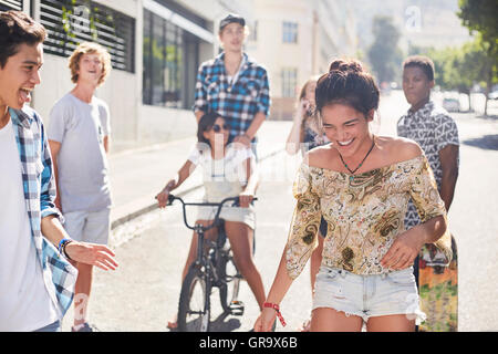Ragazza adolescente di ridere con gli amici di sunny strada urbana Foto Stock