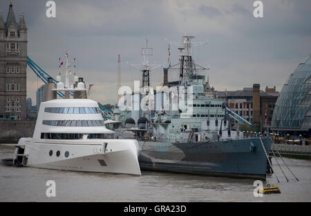 Un 390ft motor yacht appartenente al magnate russo Andrey Melnichenko, a fianco di HMS Belfast (destra) sul Fiume Tamigi a Londra. Foto Stock