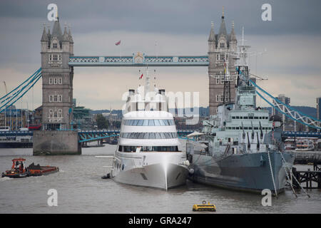 Un 390ft motor yacht appartenente al magnate russo Andrey Melnichenko, a fianco di HMS Belfast (destra) sul Fiume Tamigi a Londra. Foto Stock