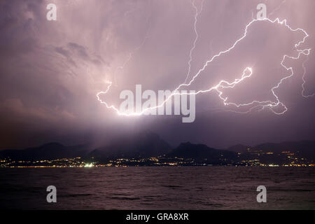 Un fulmine sul lago e monti Foto Stock