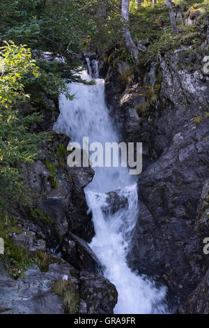 L'acqua precipita attraverso una fessura di una roccia creando una cascata di nascosto. Foto Stock