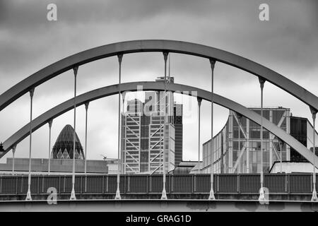 Vista del cetriolino e degli edifici circostanti sotto il cielo nuvoloso incorniciato da ponte arcuato a Londra nel mese di settembre Foto Stock