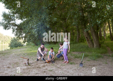 Persone campeggio in foresta, famiglia attiva in natura, Kindle fuoco, durante la stagione estiva Foto Stock