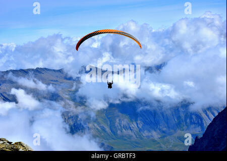 Parapendio a partire salta dalla montagna La Meije, sulle Alpi francesi, Francia Foto Stock