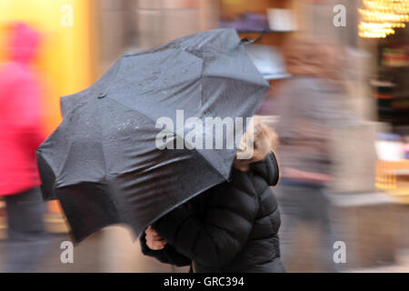 Brutto tempo con forte vento e pioggia e un ombrello Foto Stock