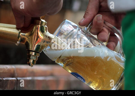 Il vetro viene riempito con la birra da un barile a Monaco di Baviera Foto Stock