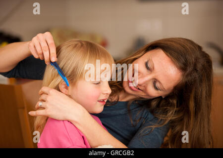 Madre pettini capelli ad una bella bambina Foto Stock