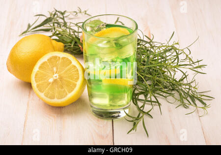Bicchiere di fresco limonata fatta in casa con il dragoncello e limone sul tavolo di legno Foto Stock
