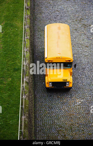 Giallo Bus fuoristrada accanto a prato verde Foto Stock