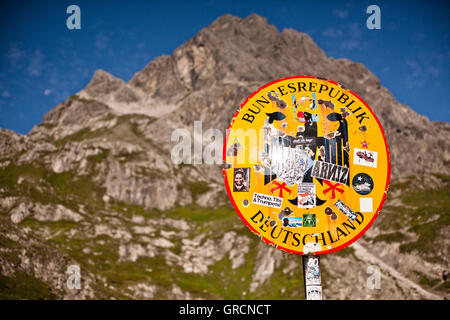 Bordersign tedesco con adesivi su un percorso nelle Alpi Foto Stock