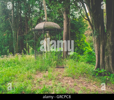 Abbandonata la statua della Madonna in un giardino Foto Stock