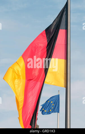 La Germania che domina l'Europa grande bandiera tedesca con piccola bandiera dell'UE oltre il Reichstag di Berlino Foto Stock