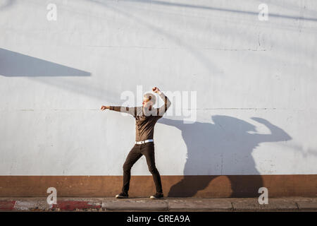 Uomo in posa sul muro bianco Foto Stock