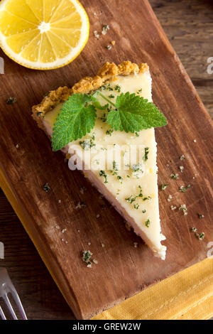 Pezzo di deliziosa casa Cheesecake al limone con menta su rustico sfondo di legno vicino fino Foto Stock