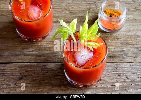 I succhi di pomodoro con sedano, spezie, sale e ghiaccio nella porzione bicchieri. Bloody Mary cocktail. Foto Stock