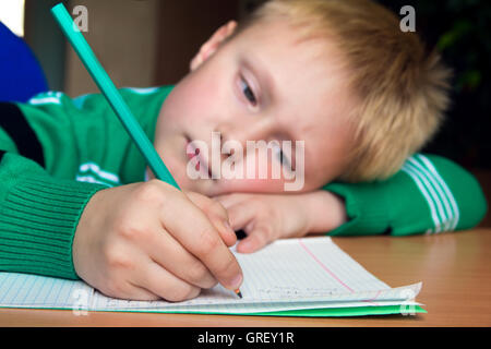 Stanco noioso ragazzo che sta facendo il suo difficile compito della scuola Foto Stock