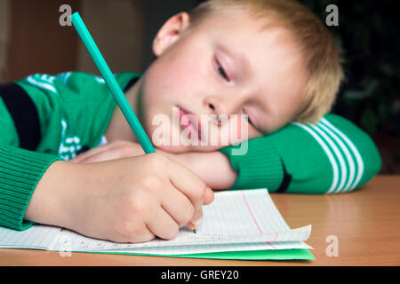 Stanco noioso ragazzo che sta facendo il suo difficile compito della scuola Foto Stock