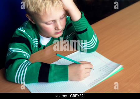 Stanco noioso ragazzo che sta facendo il suo difficile compito della scuola Foto Stock