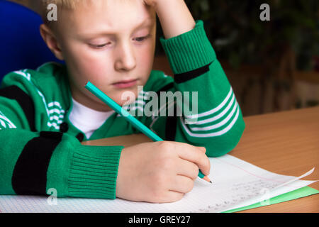 Stanco noioso ragazzo che sta facendo il suo difficile compito della scuola Foto Stock