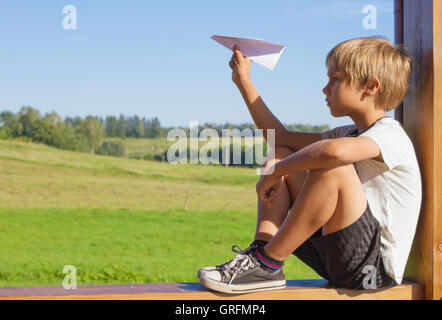 Ragazzo seduto e battenti una carta nel giorno di estate Foto Stock