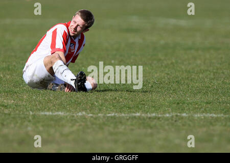 Un Bancroft United FC player è visto tenendo la sua caviglia infortunata durante un Hackney & Leyton Domenica League a Hackney Paludi - Foto Stock