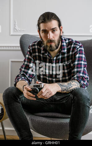 Un giovane hipster con la barba riproduce un video gioco seduto con forza nel suo volto Foto Stock