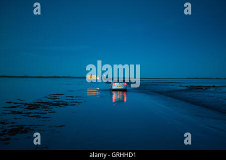 Un auto rendendo la traversata sull'Isola Santa tidal causeway al crepuscolo, Northumberland REGNO UNITO Foto Stock