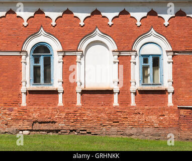 Rosso la parete in mattoni con finestre in bianco cornici decorative. Tradizionale antica architettura russa dettagli Foto Stock