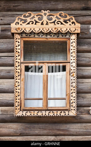 Tradizionale russo rurale antica architettura dettagli. Finestra con cornice intagliata in legno, nel muro fatto di registri ruvida Foto Stock