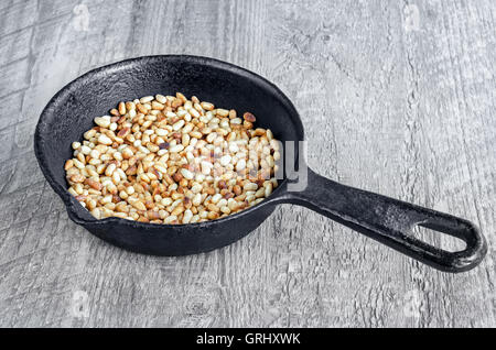 Tostare i pinoli in una padella Foto Stock