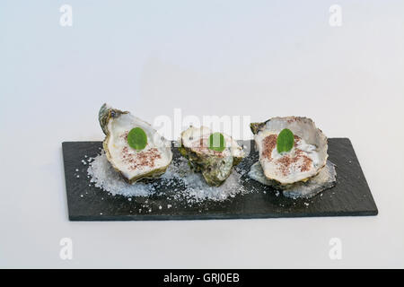 Ostriche con schiuma di mare riduzione su un letto di sale Foto Stock