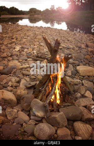 Campo di fuoco su un riverside spiaggia ghiaiosa Foto Stock