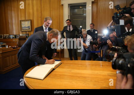 Il presidente del Consiglio europeo Donald Tusk Firma il libro degli ospiti in ufficio del Taoiseach Enda Kenny in edifici governativi a Dublino prima di avere colloqui. Foto Stock