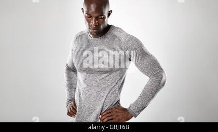Ritratto di montare il giovane africano in piedi con le mani sui fianchi e guardando verso il basso. Muscoloso e forte maschio africana di nuovo modello Foto Stock