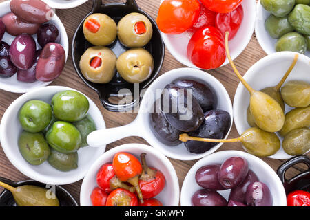 Colorato assortimento indurito di olive e peperoni rossi peperoni visualizzati in piccoli piatti individuali per spuntini ad un partito, overhead Foto Stock