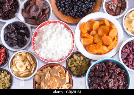 Vista da sopra di un vasto assortimento di frutta secca nei piatti individuali con Apple, noce di cocco, banana, albicocche, uva passa,i mirtilli rossi Foto Stock