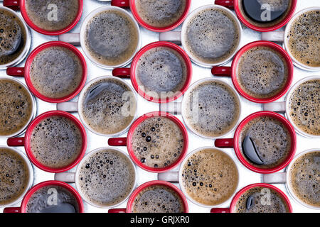 La configurazione di sfondo del rosso e del bianco tazze da caffè disposti in righe alternate riempito con spumoso preparato di fresco e versata nero co Foto Stock