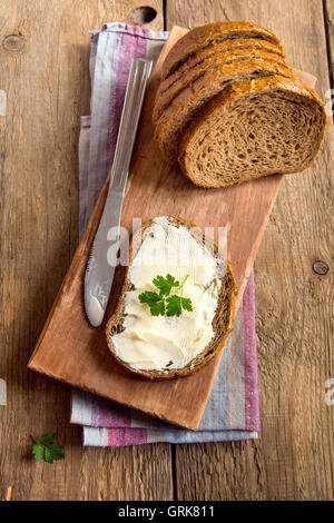 Burro e pane per la colazione, con prezzemolo oltre rustico sfondo di legno Foto Stock