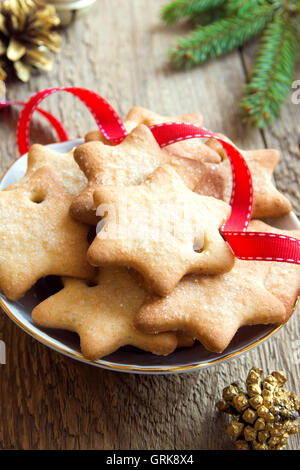 Pan di zenzero biscotti di Natale sulla tavola in legno rustico con golden coni di pino, abete rami e nastro rosso per vacanze invernali Foto Stock