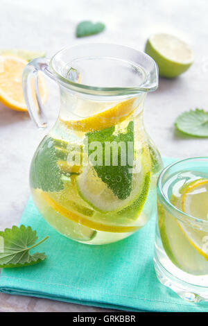 Detox acqua (limonata) con calce, limone e menta in caraffa di vetro Foto Stock