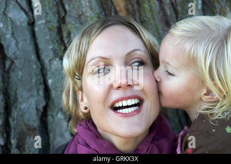 2 anno di età bimbo bacia il ridere madre. Foto Stock