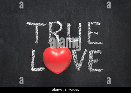 Il vero amore una frase scritta a mano sulla lavagna con il simbolo del cuore di invece di o Foto Stock