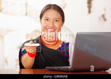 Giovani brunette indossando tradizionale nativa abiti di lavoro come receptionist hotel con un sorriso amichevole di consegnare la chiave al client attraverso escursioni, i clienti punto di vista Foto Stock